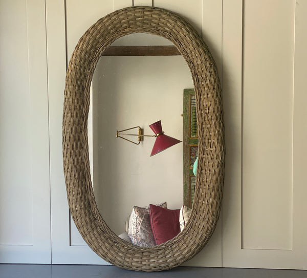 A lovely large faded green rattan mirror