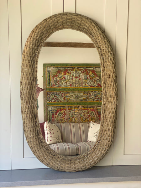A lovely large faded green rattan mirror
